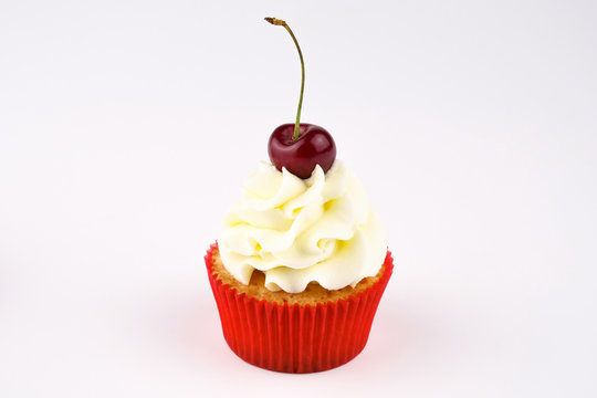 Red cupcake with white cream decorated with cherry on white background. Picture for a menu or a confectionery catalog.