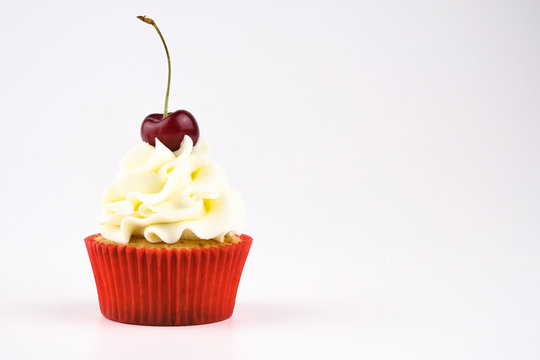 Red cupcake with white cream decorated with cherry on white background. Picture for a menu or a confectionery catalog.