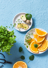 Ingredients for summer cold drink - orange slices, ginger, mint. Lemonade ingredients on blue background, top view