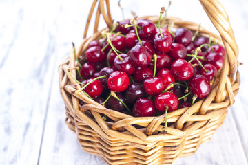A large basket of ripe cherries. Delicious and sweet berries. White wooden background, free space for text. Copy space.