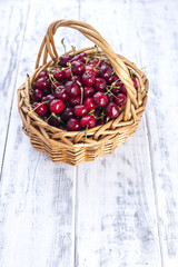 A large basket of ripe cherries. Delicious and sweet berries. White wooden background, free space for text. Copy space.
