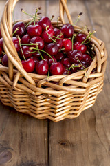 A large basket of ripe cherries. Delicious and sweet berries. Wooden background, free space for text. Retro style. Copy space