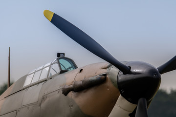 Naklejka na ściany i meble A photograph documenting the propeller and cockpit glass of an RAF Hawker Hurricane as stands on an airstrip under grey skies waiting to be flown.