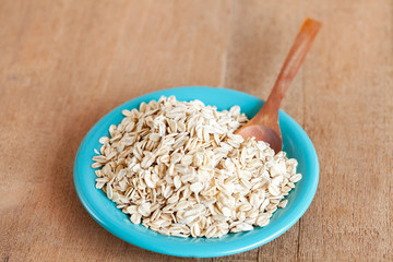 Oats flakes in dish on wood table