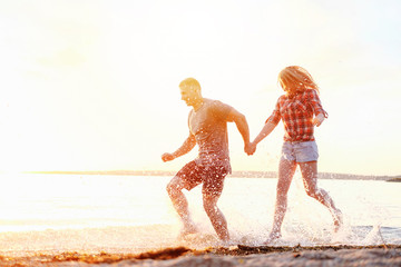 couple happy on the beach holidays run motion legs sunset splashing water