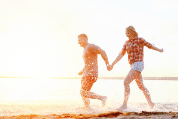 couple happy on the beach holidays run motion legs sunset splashing water