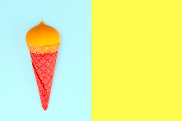 yellow ice cream in red waffle cone on blue yellow background