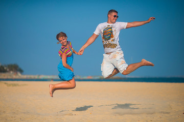 Loving couple having fun jumping on the beach