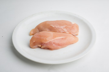 Raw chicken breast fillets on white dish