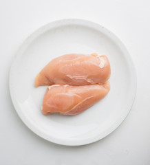 Raw chicken breast fillets on white dish