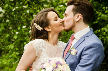 Groom and bride hugging and kissing on nature background.