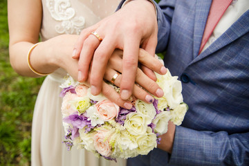 Obraz na płótnie Canvas Hands of newly married couple lies on wedding bouquet