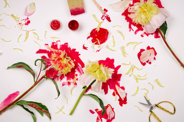 Flatlay with Honey Gold Peonies covered with red paint and other artist supplies on white