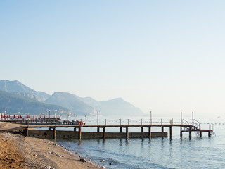 Early morning on the beach. Typical turkish hotel with sun loungers and wooden pontoon. Kemer,...