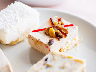 White plate full of different pastries. Tasty desserts with topping, nuts, coconut flakes.