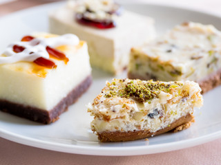 White plate full of different pastries. Tasty desserts with topping, pistachios.