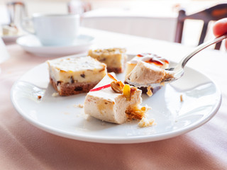 White plate full of different pastries. Tasty desserts with topping, coconut flakes.