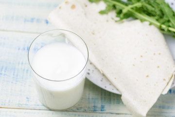 A glass of yogurt and thin Armenian bread on a plate.