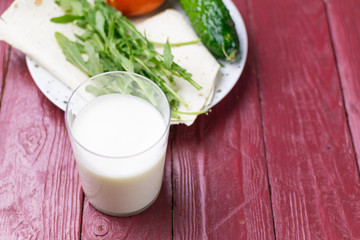 A glass of yogurt (kefir) and fresh vegetables. The concept of diet and healthy eating.