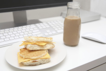 Lunchtime at a modern office desk. Delicious cheese sandwich and a fresh chocolate milk.