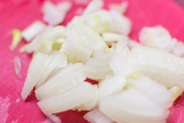 Slicing onions on a red surface.