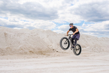 Fototapeta na wymiar Training a bicyclist in a chalky quarry. A brutal man on a fat bike.