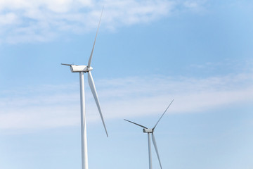 Fototapeta premium Windmill at a wind farm against blue sky background, green and renewable energy sources concept