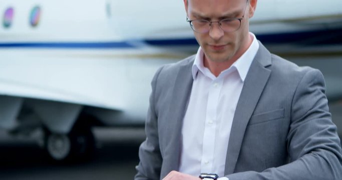 Businessman checking time while standing on a runaway 4k