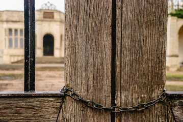 Chain locking a wooden gate outside a building.
