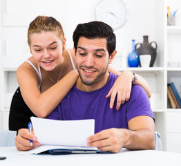 Smiling couple discussing documents at home