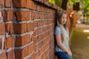 Blured girl standing near the wall and waiting. Blured background