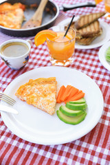 A simple breakfast of omelet, pieces of avocado and carrots, toast with cheese, a cup of coffee and a glass of fresh orange juice during a summer holiday on a yacht.