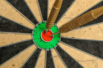 Two darts in a bullseye on a dartboard