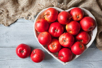 Red apples in a basket shaped like heart on a table