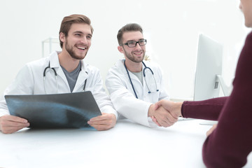 Smiling doctor at the clinic giving an handshake to his patient