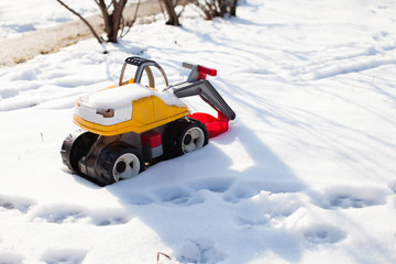 Fototapeta na wymiar Colour toy excavator in winter