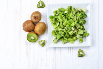 Freshly sliced kiwi fruit with whole kiwis in background.