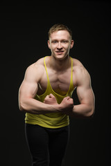 bodybuilder in a t-shirt shows biceps on a black background