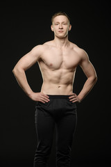 Naklejka premium a young bodybuilder shows a muscular body on a black background