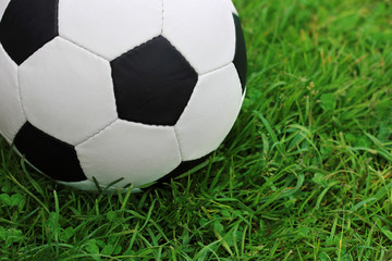 Fototapeta na wymiar Football black and white ball close-up on the green grass.