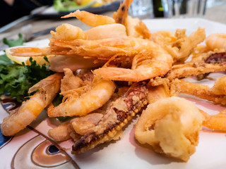 delicious Mediterranean dish of fried fish, sea food, calamari and shrimp with an ornamental lettuce leaf in a delicious dish of an Italian restaurant