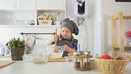 Girl baker mixes the mixture for cookies with a whisk