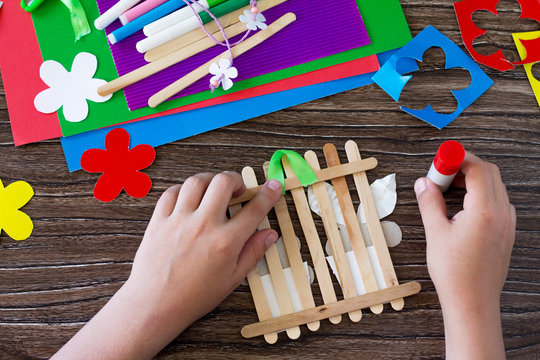 Colored paper, glue, sheets, ribbons, flowers for making a gift summer flowers on wooden sticks fence. Handmade. Project of children's creativity, handicrafts, crafts for kids.