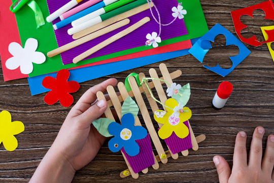 A gift of summer flowers on wooden sticks a fence on a wooden table. Handmade. Project of children's creativity, handicrafts, crafts for kids.
