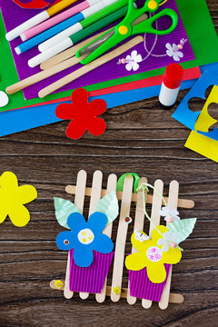 A gift of summer flowers on wooden sticks a fence on a wooden table. Handmade. Project of children's creativity, handicrafts, crafts for kids.