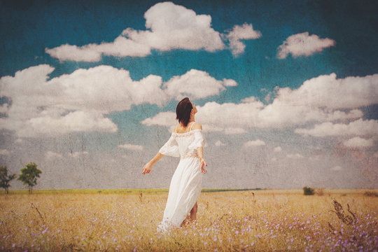 photo of beautiful young woman standing in the field on the wonderful sky background
