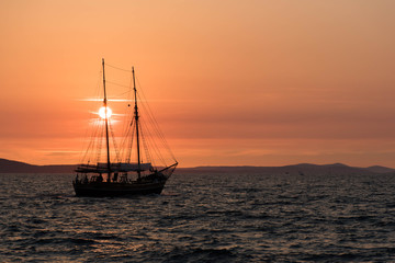 Fototapeta na wymiar Ship sailing at sunset in Croatia, crossing the sun