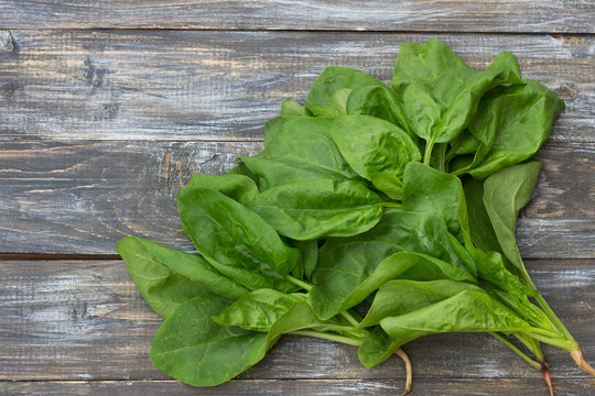 Bunch of fresh spinach with roots on a cutting board with a knife. on a wooden table. rustic style. free space