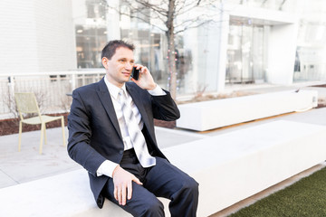 Funny, angry, irritated, confused businessman sitting on bench making face talking holding...