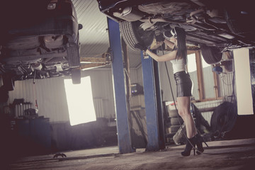 Woman mechanic is repairing a car on the lift.